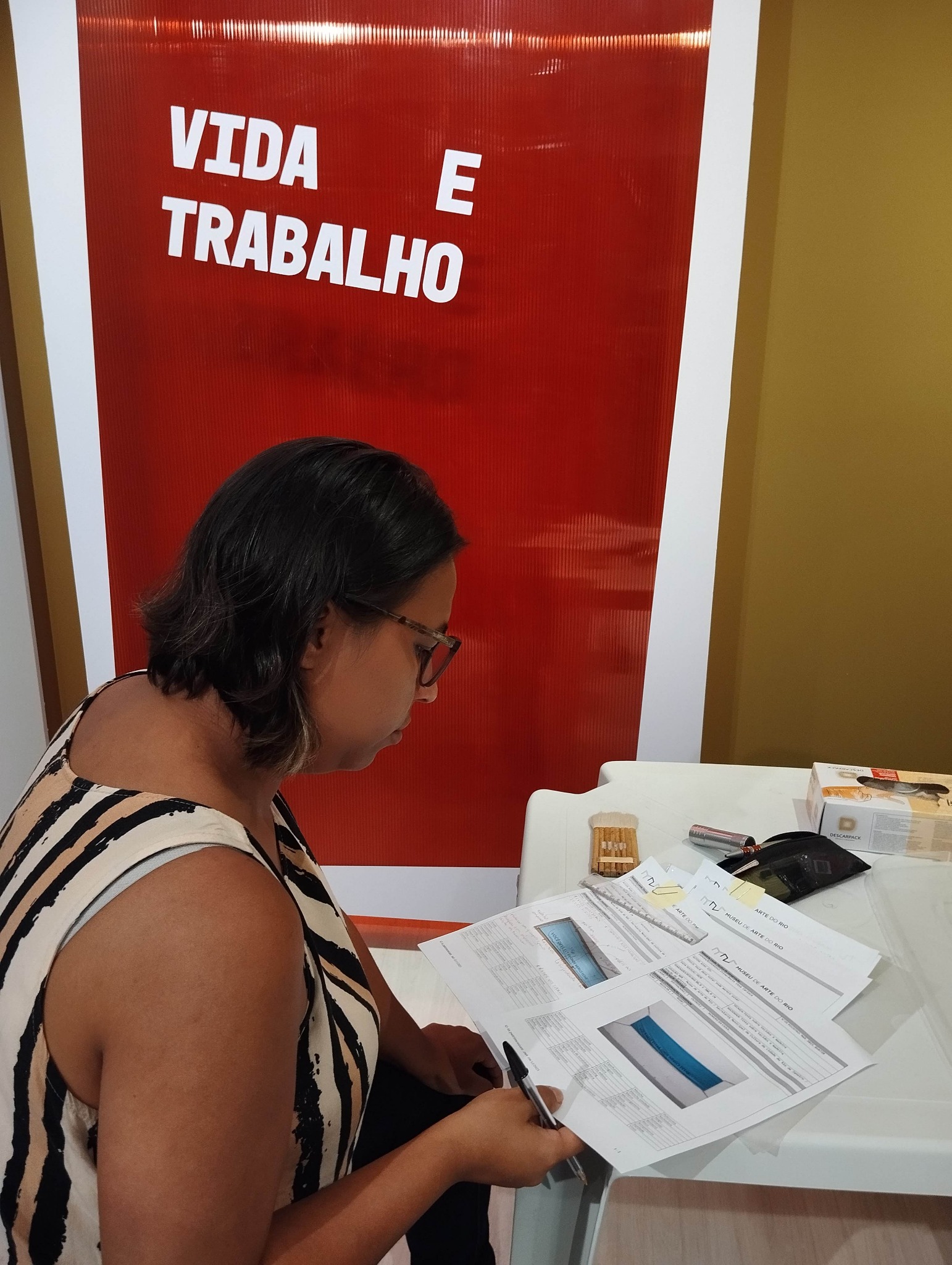 Karen Merlim trabalhando com documentos e materiais gráficos